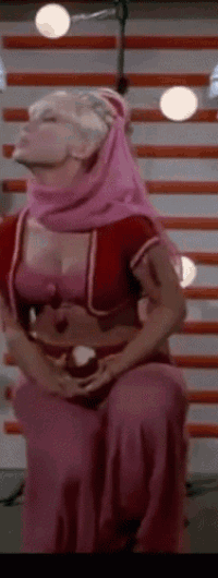 a woman in a pink dress is sitting in front of a wall