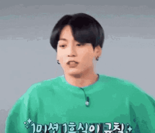 a close up of a person wearing a green shirt and a black haircut .