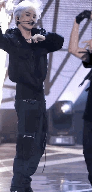 a man with white hair is standing on a stage