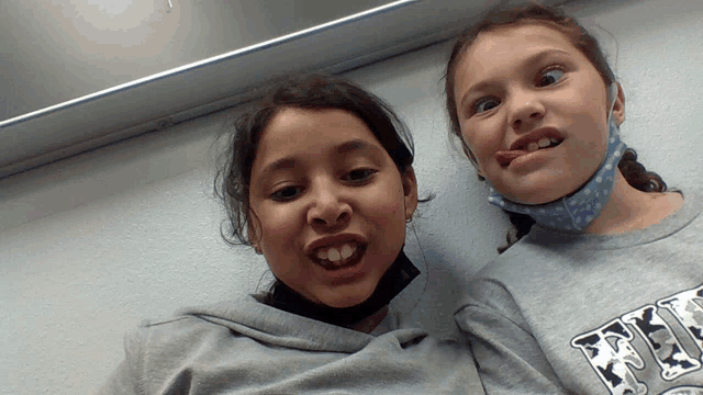 two girls making funny faces one wearing a sweatshirt that says fries