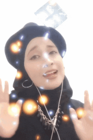 a woman wearing a hijab and a hat is making a gesture with her hands
