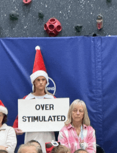 a woman holding a sign that says over stimulated