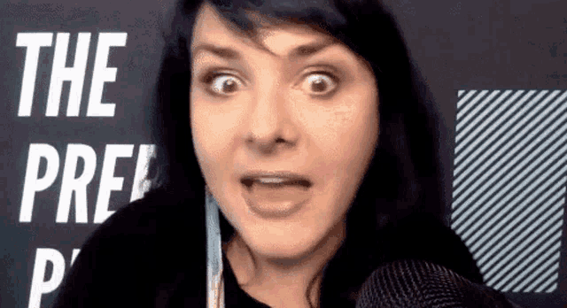 a woman is making a funny face in front of a sign that says " the pre "