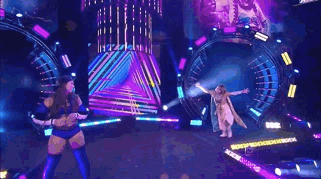 two women are dancing on a stage in front of a triangle .