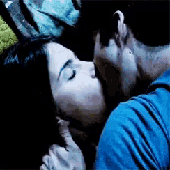 a man and a woman are kissing in a dark room .