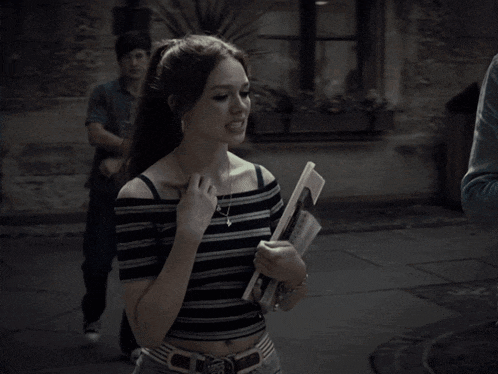 a woman in a striped top is holding a book