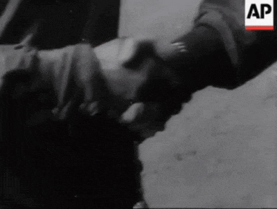 a black and white photo of two people shaking hands with an ap logo in the background