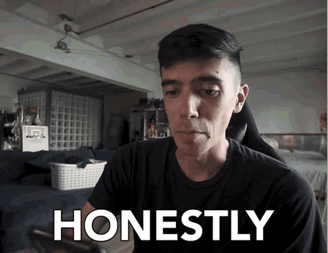a man in a black shirt is looking at his phone with the words honestly behind him