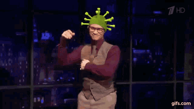 a man wearing a virus hat is dancing in front of a window
