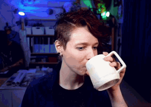 a woman is drinking from a white mug