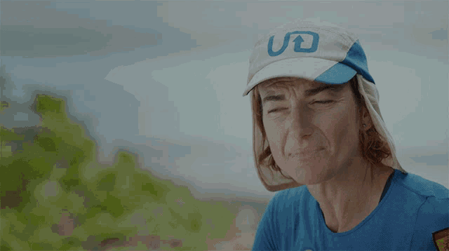 a woman wearing a blue shirt and a white hat with the word uo on it