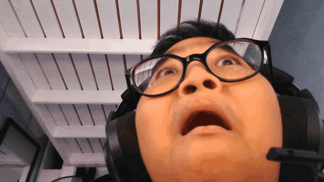 a man wearing glasses and headphones is looking up at the camera