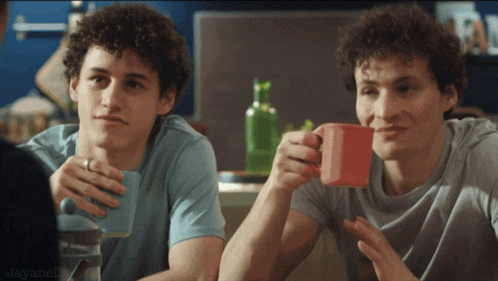 two young men sitting at a table drinking from cups with jayanen written in the lower right corner
