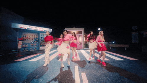 a group of girls are dancing in front of a store that says candy store