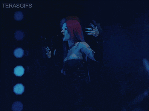 a woman singing into a microphone in front of a blue background that says terasgifs on it