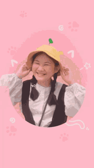 a young girl wearing a yellow hat with a green plant on it