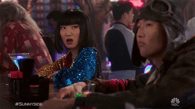 a woman in a sequined dress says dance battle while sitting at a table