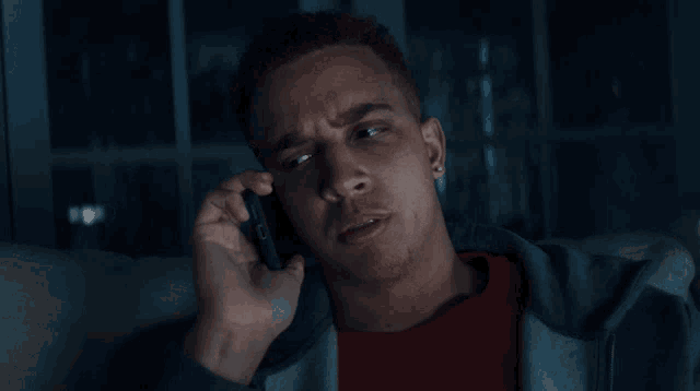 a man sitting on a couch talking on a cellphone