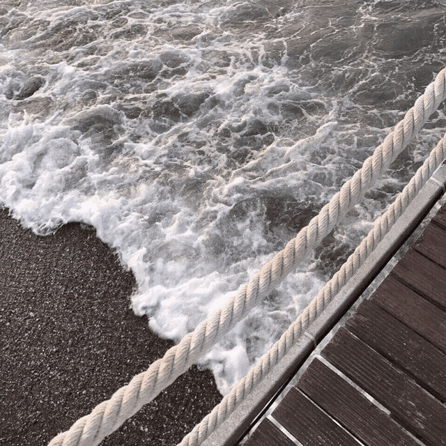 a rope runs along the edge of a wooden dock near the ocean