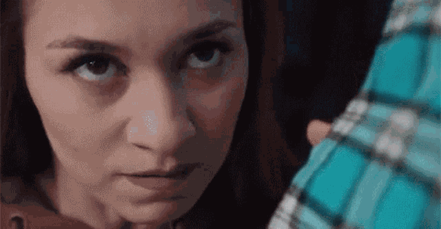 a close up of a woman 's face looking at the camera while holding a man 's arm .