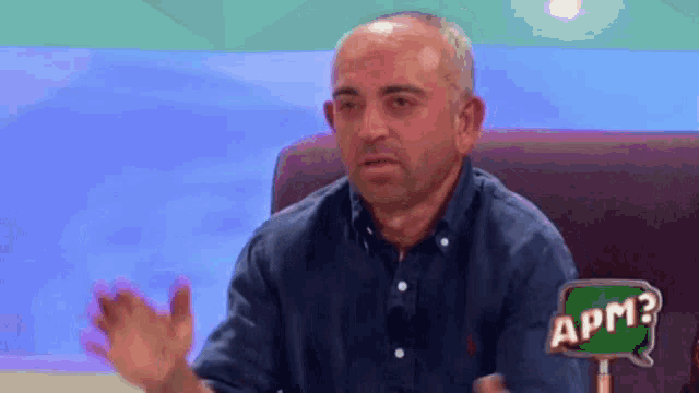 a man is sitting in a chair with a sign that says apm on it