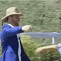 a man in a blue suit and straw hat is standing next to a woman in a blue shirt .