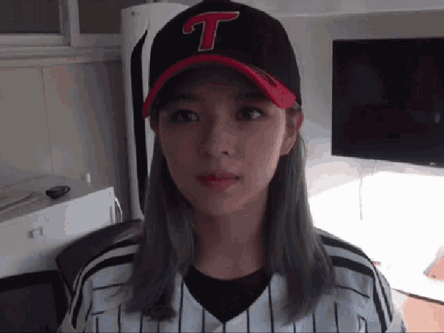 a woman wearing a baseball cap with a letter t on it