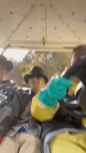 a man wearing a hat and gloves is sitting in a golf cart