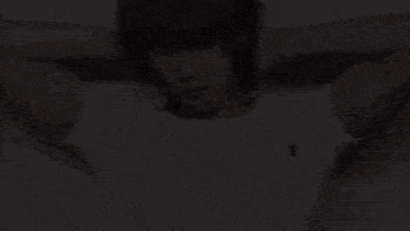 a man in a white t-shirt is holding his hands behind his head .