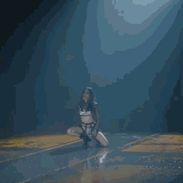a woman is kneeling down in a dark room under a light