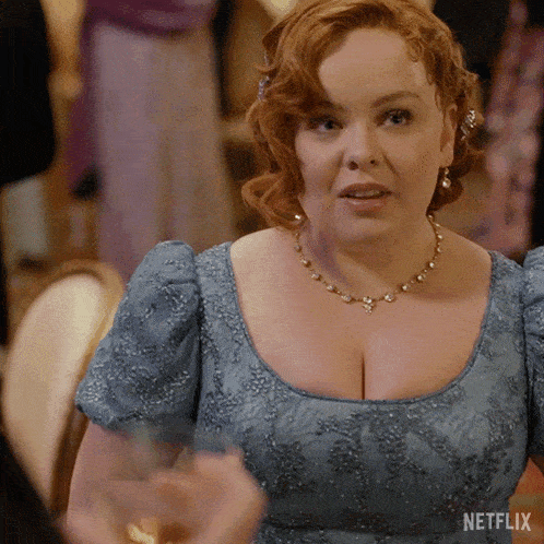 a woman wearing a blue dress and a necklace with netflix written on the bottom right