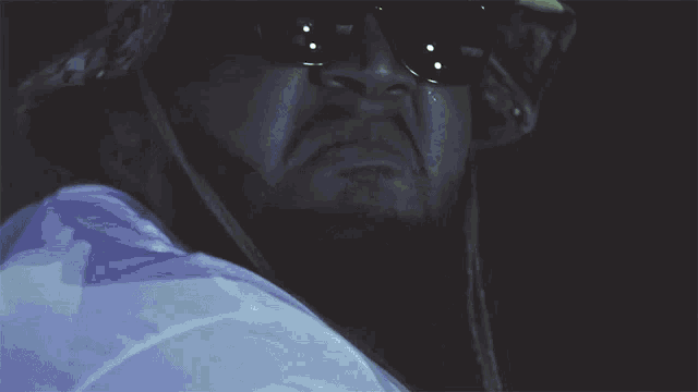a man wearing a hat and sunglasses is making a face