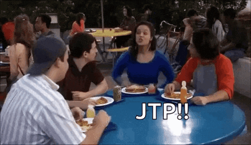 a group of people are sitting at a table with plates of food and drinks .