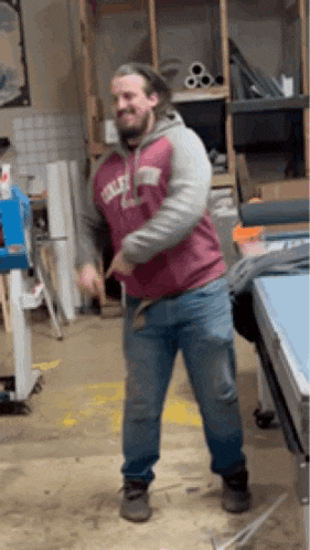 a man in a red and gray sweatshirt is dancing in a room .