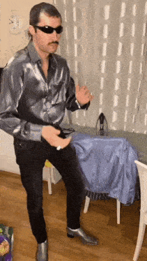 a man wearing sunglasses and a mustache is standing in a room .