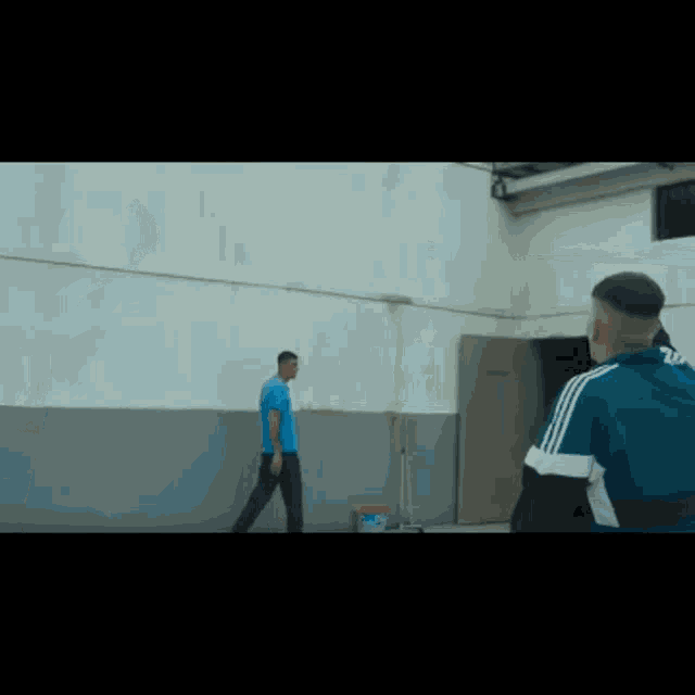 two men are standing next to each other in front of a white wall .