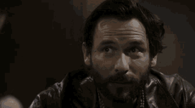 a man with a beard and a leather jacket is looking up