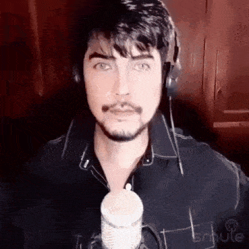 a man with a beard is standing in front of a microphone wearing headphones .