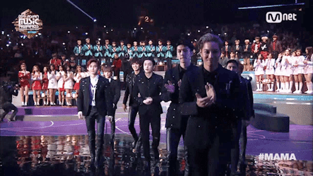 a group of people standing on a stage at a mnet music awards show