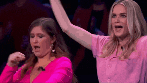 two women are standing on a stage with their arms in the air .