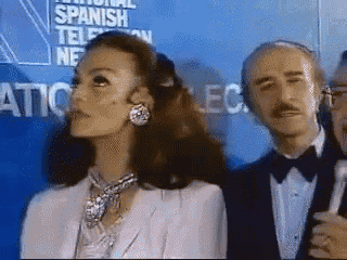 a man and a woman are standing in front of a sign that says national spanish tele network