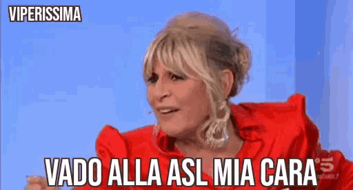 a woman in a red shirt is making a funny face and says vado alla asl mia cara