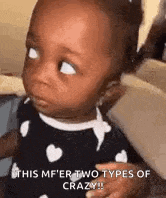 a baby girl is making a funny face while looking at the camera .