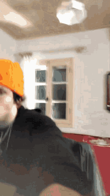 a man wearing an orange hat is standing in a room