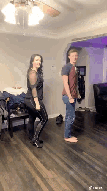 a man and a woman are dancing in a living room with tiktok written on the bottom of the screen