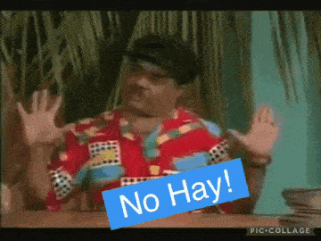 a man sitting at a table with his hands up and a sign that says no hay