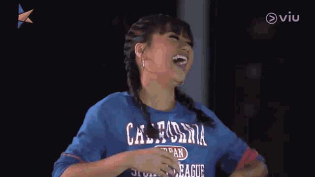 a woman wearing a blue shirt that says urban sports league laughs