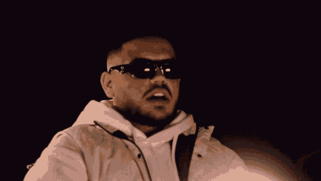 a man wearing sunglasses and a white jacket with a hood