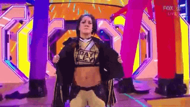 a woman in a wrestling outfit is standing on a stage holding a jacket over her shoulder .