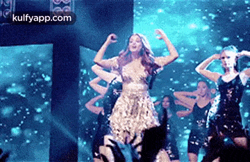 a woman in a dress is dancing on a stage in front of a crowd of people .